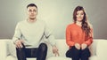 Shy woman and man sitting on sofa