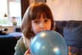 A shy young girl hiding behind a balloon