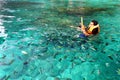 Sian man in orange life jacket with diving mask snorkeling among many Indo-Pacific sergeant fish on Andaman Sea