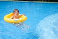 Sian 2 years old toddler boy child having fun playing with inflatable swim ring in outdoor swimming pool on hot summer day Royalty Free Stock Photo