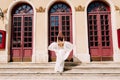 Sibenik, Croatia - 05.06.17: Bride in a white dress fluttering in the wind stands in front of high glass doors to an