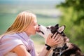 Siberian husky licks in the face of his mistress, who hugs him against the backdrop of a forest road on a sunny day Royalty Free Stock Photo