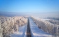 Siberian rural asphalt road under the snow. Siberian rural winter landscape with birch trees covered with hoarfrost. Aerial shot Royalty Free Stock Photo