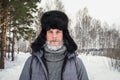 Siberian Russian man with a beard in hoarfrost in freezing cold in the winter freezes and wears a hat with a earflap Royalty Free Stock Photo