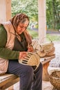 An old Romanian woman weaves wicker baskets