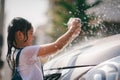 Sibling Asian girls wash their cars and have fun playing indoors on a hot summer day