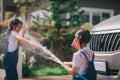 Sibling Asian girls wash their cars and have fun playing indoors on a hot summer day