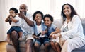 Sibling brothers playing video games together while sitting with their family. African american family of five having