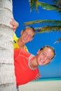 Siblings behind palm tree Royalty Free Stock Photo