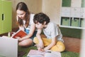 Siblings brother sister attractive girl teenager and tween boy do homework learn foreign language writing in pupil book with Royalty Free Stock Photo