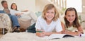 Siblings doing their homework on the floor with parents behind t Royalty Free Stock Photo