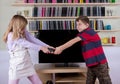 Siblings fighting for the remote control in front of the TV Royalty Free Stock Photo