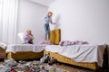 siblings having fun, laughing, boy and girl play pillow fight in messy childrens room, kids playing among the many toys Royalty Free Stock Photo