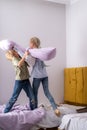 siblings having fun, laughing, boy and girl play pillow fight in messy childrens room, kids playing among the many toys Royalty Free Stock Photo