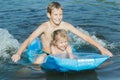 Siblings having fun during summer sea bathing with robin egg blue pool air mat outdoor Royalty Free Stock Photo