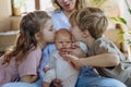 Siblings kissing the cheeks of a little baby. Big brother and big sister meeting newborn sister, enjoying together time. Royalty Free Stock Photo