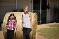 Siblings leaning on hay in the farm