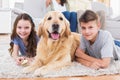 Siblings lying with dog while parents relaxing on sofa