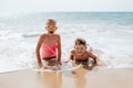 Siblings playing on beach, lying in water, having fun. Smilling girl and boy in swimsuits, swimming googles on sandy Royalty Free Stock Photo