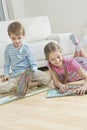 Siblings reading story books on floor in the living room