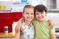 Siblings standing with arm around in kitchen