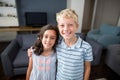 Siblings standing with arm around in living room