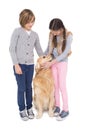 Siblings standing and petting their golden retriever