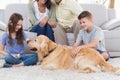 Siblings stroking dog while parents sitting on sofa Royalty Free Stock Photo