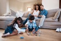 Siblings are there to help each other out. two young siblings playing with their toys while their parents sit and watch Royalty Free Stock Photo