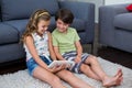 Siblings using digital tablet in living room Royalty Free Stock Photo