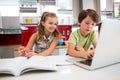 Siblings using laptop while doing homework in kitchen Royalty Free Stock Photo