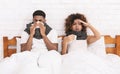 Sick african-american couple blowing noses in bed Royalty Free Stock Photo