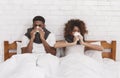 Sick african-american couple blowing noses in bed Royalty Free Stock Photo