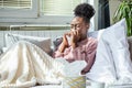 Sick African American woman with headache sitting under the blanket. Sick woman covered with a blanket lying in bed with seasonal Royalty Free Stock Photo