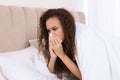 Sick African American woman with tissue in bed at home Royalty Free Stock Photo