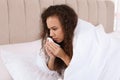 Sick African American woman with tissue in bed at home Royalty Free Stock Photo