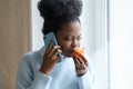 Sick afro woman trying to sense smell of half fresh tangerine orange talking on phone. Covid-19