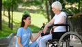 Sick aged woman in wheelchair looking at female volunteer, support and care