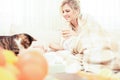 Sick, allergic young woman petting her cat while wrapped in a cozy blanket in living room Royalty Free Stock Photo