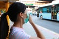 Sick asian child girl wearing protection mask against air pollution at bus stop in the city Bangkok,inhale fine dust,pm 2.5,female