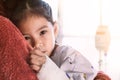 Sick asian child girl who have IV solution hugging her mother