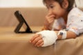 Sick asian little child girl who have IV solution bandaged playing digital tablet to relax