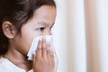 Sick asian child girl wiping and cleaning nose with tissue