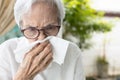 Sick asian senior woman having a cold,runny nose stuffy nose,old elderly blowing or wiping nose in a paper handkerchief,rhinitis,