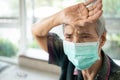 Sick asian senior woman touching her forehead,check the body temperature,illness and fever,tired,exhausted elderly patient wear a