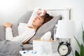 Sick Asian woman with cold sleeping on bed at home with high fever suffering from insomnia and medicine in foreground Royalty Free Stock Photo