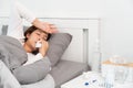 Sick Asian woman with cold sleeping on bed at home with high fever suffering from insomnia and medicine in foreground Royalty Free Stock Photo