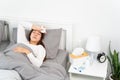 Sick Asian woman with cold sleeping on bed at home with high fever suffering from insomnia and medicine in foreground Royalty Free Stock Photo