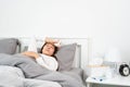 Sick Asian woman with cold sleeping on bed at home with high fever suffering from insomnia and medicine in foreground Royalty Free Stock Photo