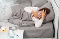 Sick Asian woman with cold sleeping on bed at home with high fever suffering from insomnia and medicine in foreground Royalty Free Stock Photo